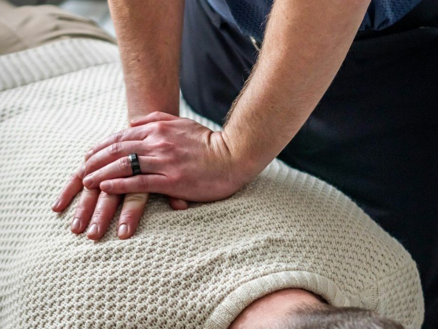 A therapist's hands pressing on a patient's spine