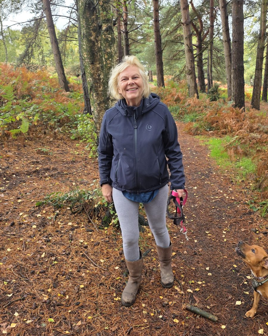 Sue Coffee smiling on a woodland walk with her dog